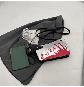 Detail of cleaver-shaped shoulder bag featuring silver mirror finish and red splatter pattern