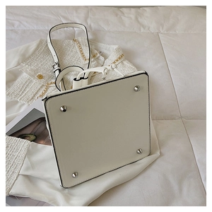 Detail view of white leather bag bottom with four protective metal feet on quilted fabric