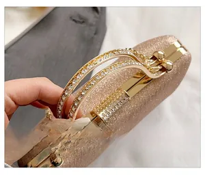 Close-up of sparkling evening bag with rhinestone double ring handles in rose gold