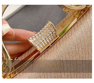 Macro detail of the elegant champagne evening bag featuring a rhinestone-encrusted metal clasp