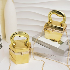 Goldene Abendtasche aus Acryl mit Metallgriffen und Kettenriemen auf Modebüchern