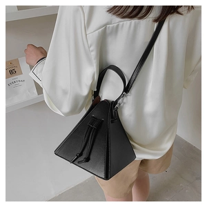 Detail of a black triangular pyramid bag with drawstring closure and leather shoulder strap
