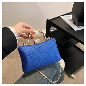 Detail of blue glitter evening clutch bag with gold handle and crystal clasp on display