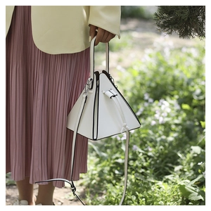 Close-up of a white pyramid handbag with black trim and a delicate shoulder strap