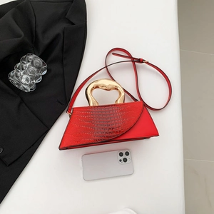 Red trapezoid handbag with gold ring handle and crocodile texture flap on white background