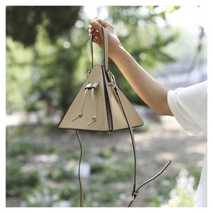 Detail of beige pyramid handbag with drawstring closure and detachable shoulder strap