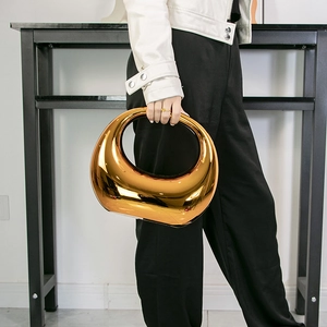 Metallic bronze crescent handbag with mirror finish in a futuristic minimalist style