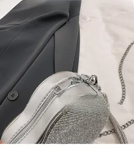 Détail du sac cœur en strass argenté avec fermeture éclair et bandoulière en chaîne