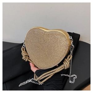 Détail de la pochette dorée en forme de cœur avec strass brillants et chaîne élégante