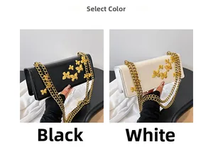 Detail view of black and white crossbody bags with golden butterfly relief and chain