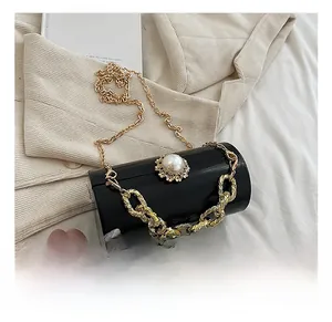 Detail of black cylindrical clutch with gold chain and large pearl flower embellishment