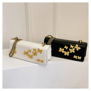 Detail of black and white leather crossbody bags with golden butterfly embellishments