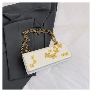Detail of white leather crossbody bag featuring gold 3D butterfly accents and chunky chain