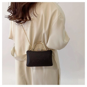 Detail of black glitter evening clutch featuring gold round handle and chain strap