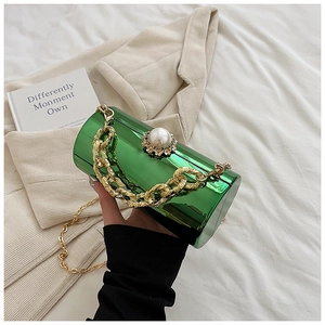 Detail of emerald acrylic cylinder bag with pearl buckle and gold chain strap