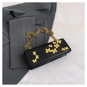 Close-up of black leather square bag with gold butterfly accents and chunky chain strap