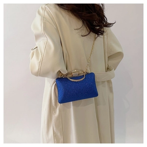 Close-up of royal blue sequined evening bag with gold handle on beige coat