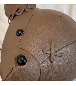Macro shot of dark brown lychee leather texture and thick stitching on bear backpack