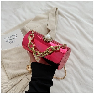Detail of fuchsia acrylic cylinder clutch with pearl clasp and gold chain strap