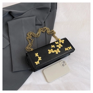 Detail of black crossbody bag with golden butterfly charms and metallic chain strap