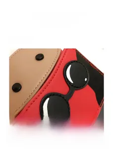 Close-up of red PU leather bag featuring unique black cartoon goggle patch and stitching