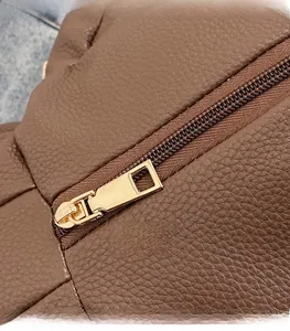 Close-up of brown litchi pattern leather texture and gold metal zipper on a backpack