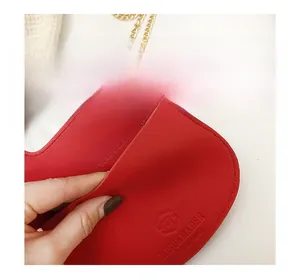 Detail of red leather mini bag with gold chain strap and embossed logo texture