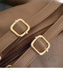 Detail of dark brown lychee leather texture and shiny golden hardware buckles