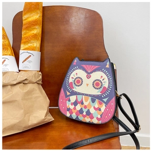 Detailed close-up of a purple owl-shaped crossbody bag on a rustic wooden chair