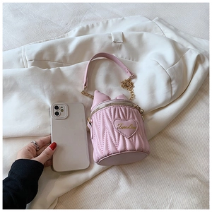 Détail du mini sac cylindrique rose matelassé avec patch coeur et chaîne dorée