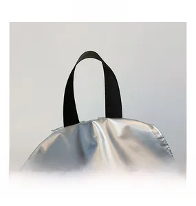 Detail of silver metallic fabric and durable black nylon handle of the backpack