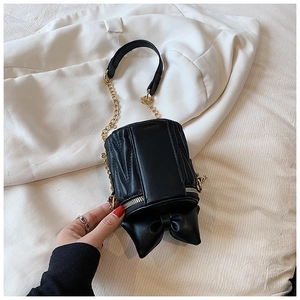 Détail d'un petit sac seau noir plissé avec grand nœud décoratif et bandoulière dorée