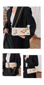 Detailed view of white leather crossbody bag with decorative golden metal butterflies