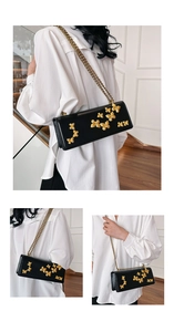 Detail of elegant black crossbody bag featuring 3D gold butterfly embellishments and chain