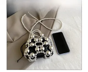 Mini silver beaded bag with black drawstring liner and chain strap next to a smartphone