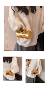 Close-up of golden cylindrical acrylic clutch with metallic chain and pearl clasp detail