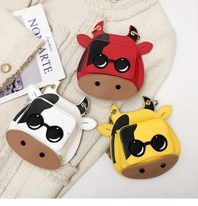 Flat-lay detail of mini cow cross-body bags in red, white and yellow with sunglasses