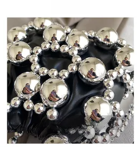 Detail of black pleated bag with silver metallic sphere mesh overlay and industrial style