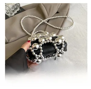 Detail of mini black leather bag with silver metallic beads and beaded shoulder strap