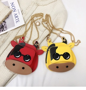 Detailed view of red and yellow cartoon cow mini crossbody bags with gold chain straps