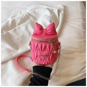 Détail du sac cylindrique rose en similicuir surpiqué en V avec un gros nœud