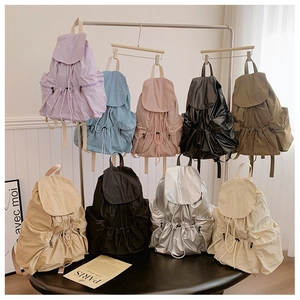 Detail showing various colors of pleated nylon backpacks with flap and drawstring closure