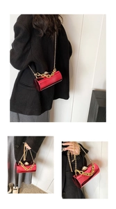 Detail of red patent leather bucket bag with large pearl handle and gold chain strap