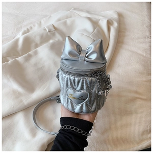 Gros plan détaillé du mini sac seau argenté avec nœud, broderie cœur et bandoulière