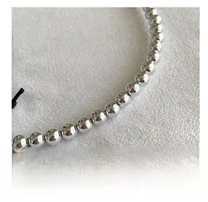 Macro detail of high-shine silver metallic beaded shoulder strap on white fabric