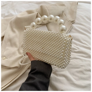 Detailed view of handmade pearl woven handbag with large bead handle and crossbody strap