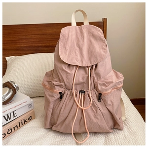 Detail of dry rose pink pleated nylon backpack with flap drawstring and zip side pockets