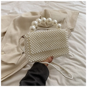 Detail of handmade white pearl woven handbag with large bead handle and chain strap