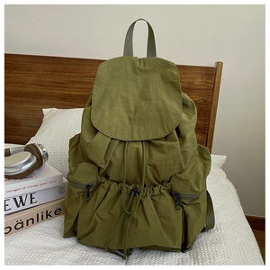 Detail of army green pleated nylon backpack with drawstring closure and side zip pockets