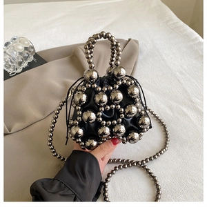 Detail of black leather drawstring bag with silver bead embellishments and pearl handle